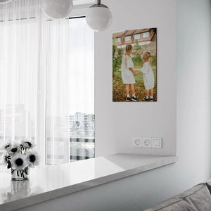 vertical wooden portrait of two sisters in matching polka dot dresses displayed in minimal white interior with globe pendant lights and window ledge decorated with anemone flowers